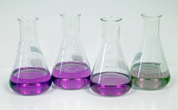 El Erlenmeyer Frasco cónico en laboratorio de banco, con reacción de formación de disolvente verde y púrpura entre ácido bórico y concentración de análisis de solución de amoníaco en la muestra de aguas residuales. Enfoque selectivo. - Foto, Imagen
