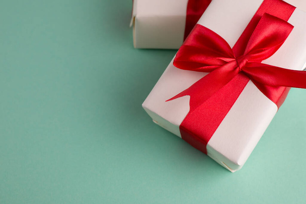Kaksi valkoista lahjapakkausta, jotka on sidottu kirkkaanpunaisilla jousilla sinisellä pohjalla ja tekstillä. Hyvä joulun ja uudenvuoden bannerit. - Valokuva, kuva