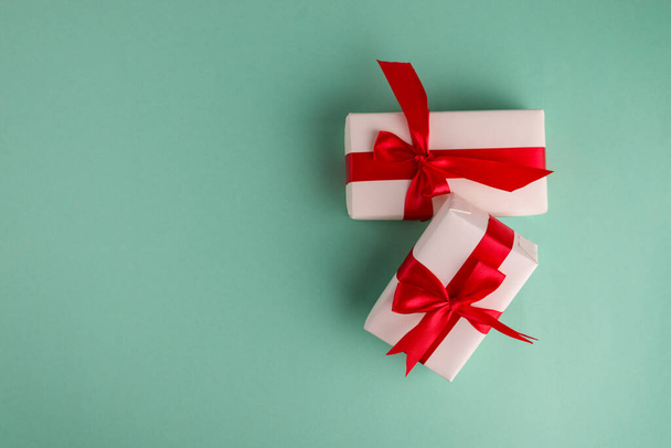 Zwei weiße Geschenkboxen gebunden mit leuchtend roten Schleifen auf aqua-blauem Hintergrund und Platz für Text. Gut für Weihnachten und Neujahr. - Foto, Bild
