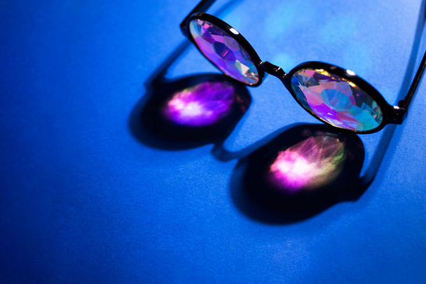 Калейдоскопічні окуляри в променях світла на багатому синьому фоні
 - Фото, зображення