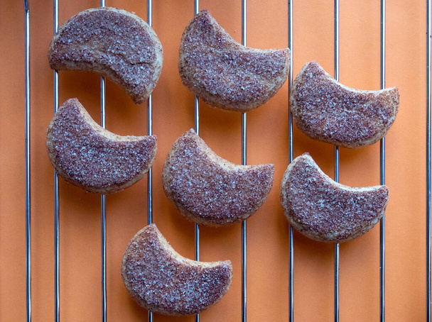 Eine Reihe verführerischer halbherziger kandierter Kekse, die auf einem Metallrost liegen, weiche Schatten, natürliches Licht - Foto, Bild