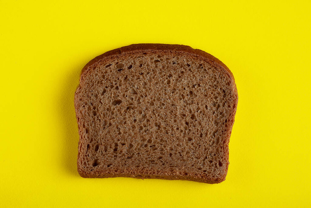 Fresh delicious slice of rye bread on a yellow background - Foto, afbeelding