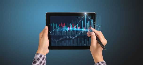 Hand holding tablet and showing holographic graphs stock market statistics gain profits. Concept of growth planning business strategy - Фото, изображение