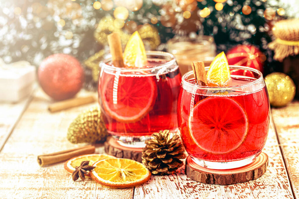 Heißes Wintergetränk, Weihnachtswein mit fröhlichen Farben und Lichtern. Getränk mit Zimt und Zitrusfrüchten. Bekannt als Glühwein, spanische Sangria, Glogg und Glhwein - Foto, Bild
