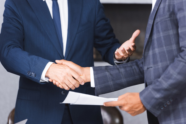 Cropped view of african american businessman holding documents and shaking hands with colleague - Foto, immagini