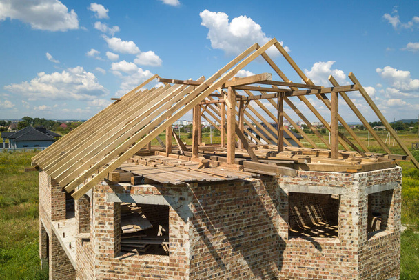 Vista aérea da casa inacabada com estrutura de estrutura de telhado de madeira em construção. - Foto, Imagem