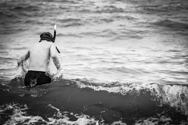 Un ragazzo che cammina verso il mare, indossa uno snorkeling e una maschera, orientamento paesaggistico - Foto, immagini