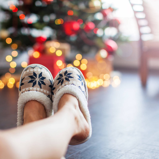 Legs in slippers on Christmas tree background - Foto, Imagem