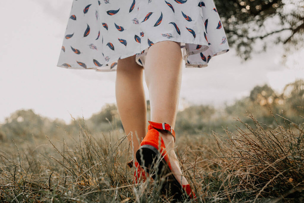 Mujer en vestido camina por el césped, bailando y divirtiéndose en la hierba - Foto, imagen