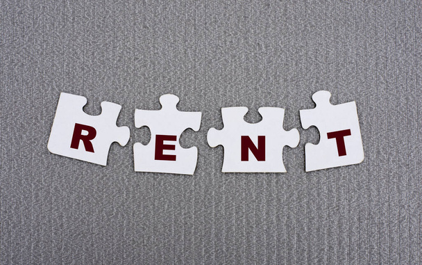 RENT - word composed of paper white puzzles on a gray background. Business concept - Foto, immagini