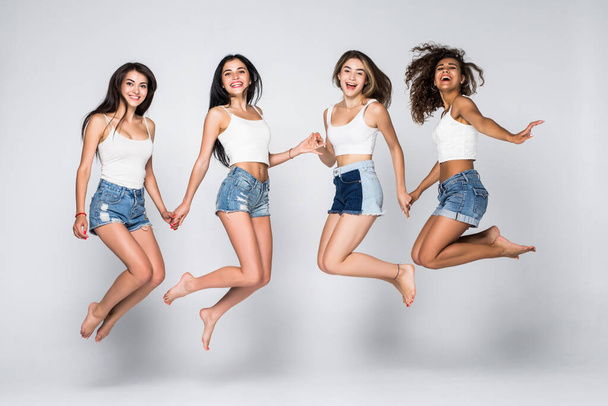 Skupina veselých mladých žen skákajících do vzduchu. Izolováno na bílém pozadí - Fotografie, Obrázek