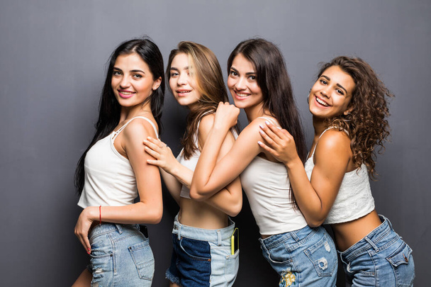 four attractive multiethnic women in white shirts embracing isolated on grey - Photo, Image