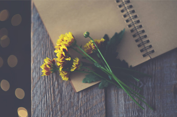 Autumn still life. Old vintage notebook with yellow flowers. Toned image. Flat lay, top view, copy space. - Фото, изображение
