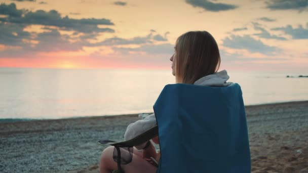 Γυναίκα πίνει από θερμός και κάθεται σε ξαπλώστρες στην παραλία - Πλάνα, βίντεο