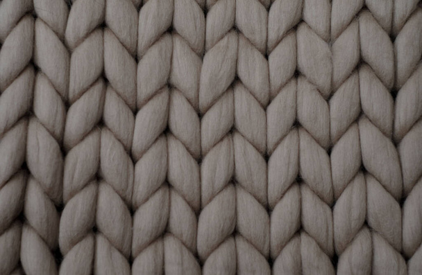 Beige knitted background. Woolen fabric with pattern of braids. - Photo, Image