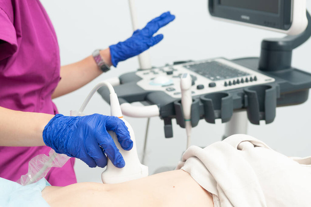 Ultraschalldiagnostik des Bauches der Frau in der Klinik, Nahaufnahme. Arzt führt Ultraschallsensor über Patientin-Magen und betrachtet Bild auf Bildschirm. - Foto, Bild