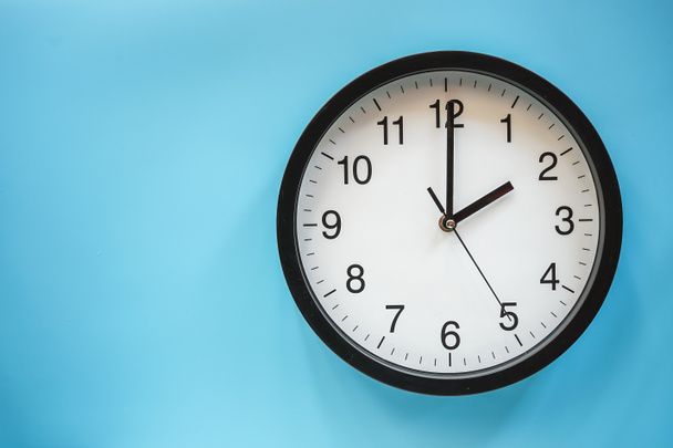 Horloge analogique classique noir et blanc sur fond bleu  - Photo, image