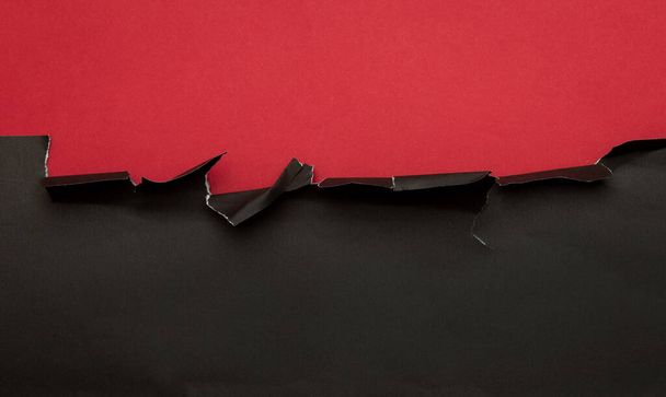 Kırmızı arka planda siyah yırtık bir kağıt. Kara Cuma kampanyası. - Fotoğraf, Görsel
