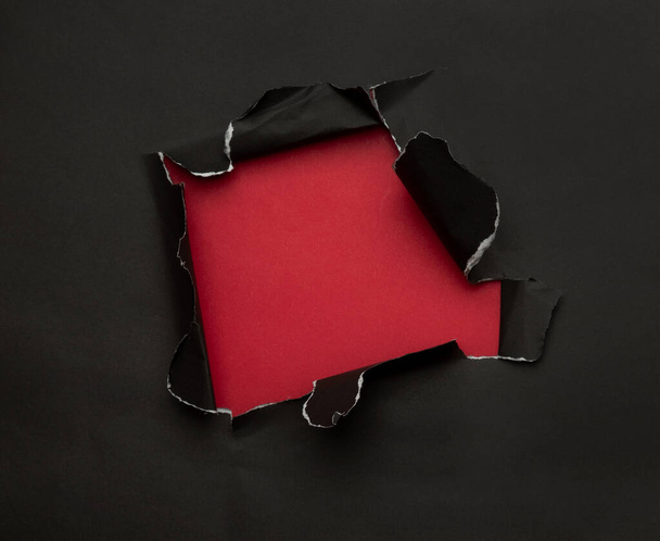 Kırmızı arka planda siyah yırtık bir kağıt. Kara Cuma kampanyası. - Fotoğraf, Görsel
