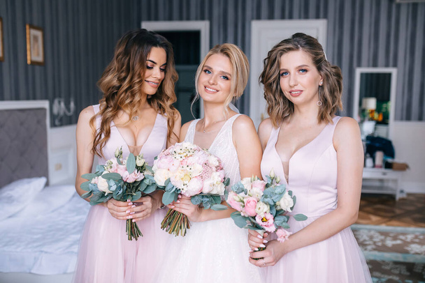 A gorgeous bride with her girlfriends are holding flowers. - Fotografie, Obrázek