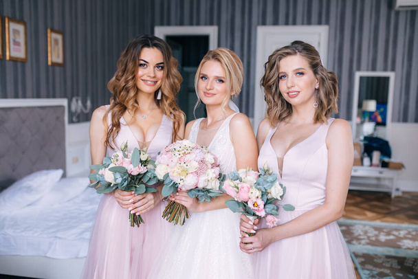 A gorgeous bride with her girlfriends are holding flowers. - Foto, Bild