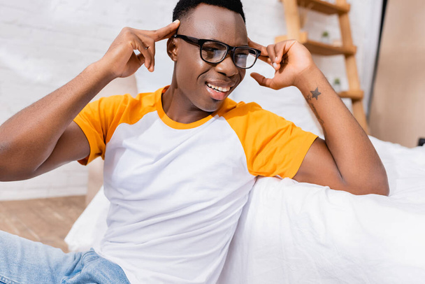 Afričan Američan muž v brýlích dívá pryč blízko postele doma  - Fotografie, Obrázek