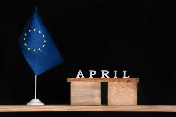 Calendario in legno di aprile con bandiera UE su sfondo nero. Vacanze dell'Unione europea in aprile. - Foto, immagini