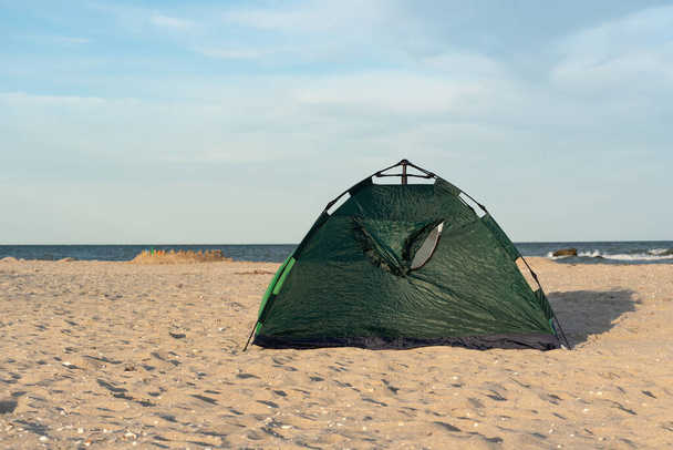 Vihreä teltta hiekkarannalla. Telttailemassa merellä teltan kanssa. Matkustaminen. - Valokuva, kuva