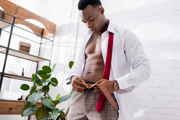 Homme d'affaires afro-américain musclé portant une ceinture à la maison  - Photo, image