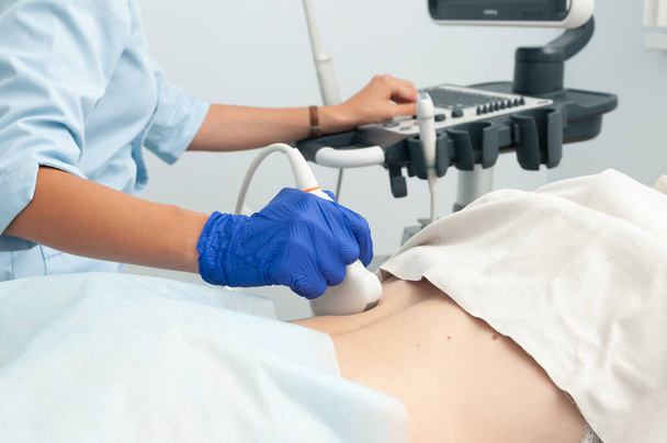 Böbreklerin ultrason araştırması. Doktor kızın sırtındaki ultrason sensörünü çalıştırıyor.. - Fotoğraf, Görsel