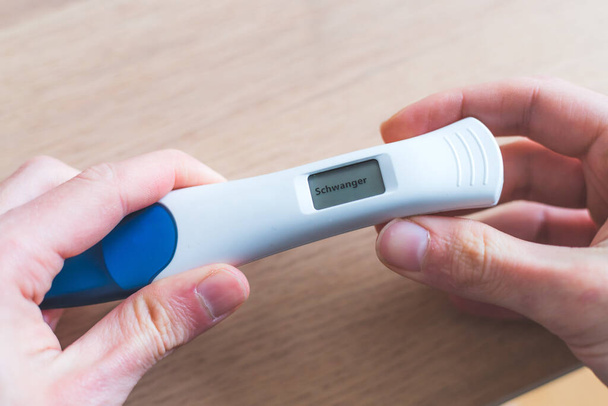 Woman hand holding pregnancy test, result is pregnant,Schwanger - Photo, image