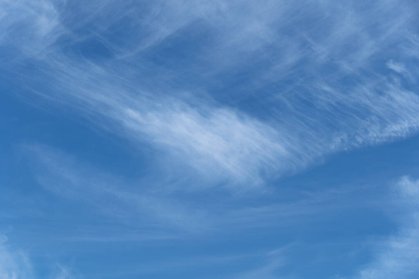 Jasne błękitne niebo z kilkoma białymi chmurami w zygzakowatym wzorze - Zdjęcie, obraz