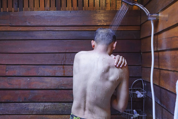 New normal for Asian man's showering in bathroom for clean a body and relax by bare and water drops from shower to the head and all body, Asian men bathing in the bathroom. - Fotó, kép