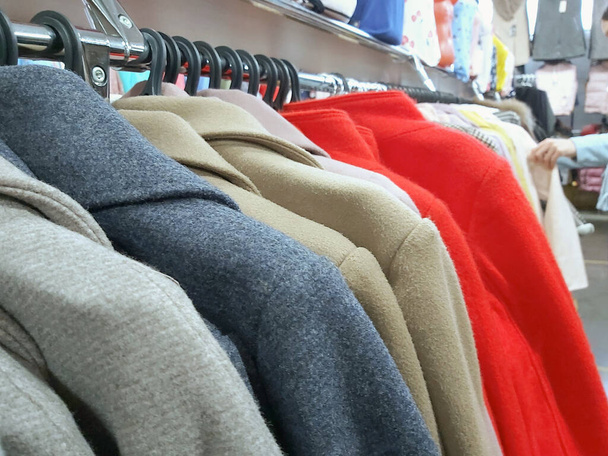 μια σειρά από γυναικεία παλτά στο κατάστημα σε κρεμάστρες. - Φωτογραφία, εικόνα