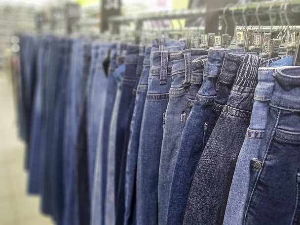 стильные джинсовые брюки в магазине одежды на стендах. - Фото, изображение