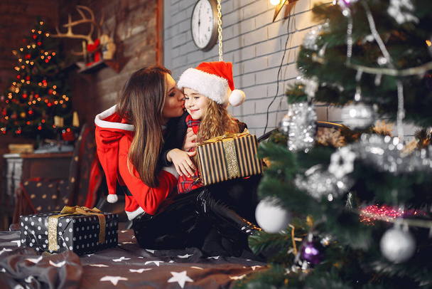 Mother in a santas suit with cute daughter at home - Fotoğraf, Görsel