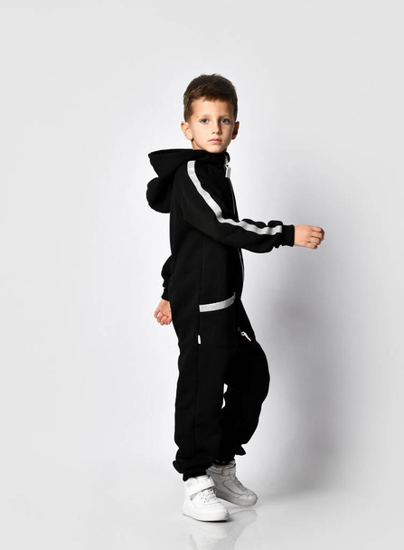 Boy wearing black warm jumpsuit in motion shot - Фото, изображение