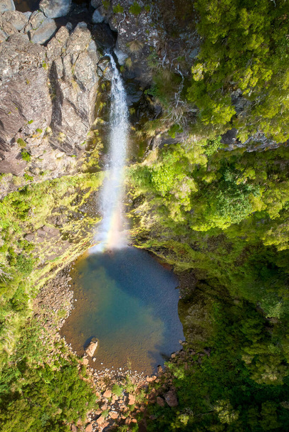 Veduta aerea e verticale della cascata Risco, caduta sul lago sul fondo di un ripido canyon ricoperto di verde vegetazione. Sfondo naturale. Escursioni sull'isola di Madeira, Portogallo. - Foto, immagini