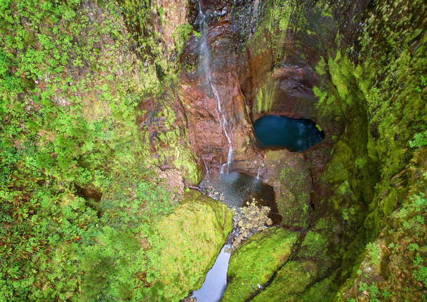 Aerial view of Risco waterfall, falling from fog to steep canyon covered in green vegetation. Nature background. Hiking on Madeira island, Portugal. - Photo, Image