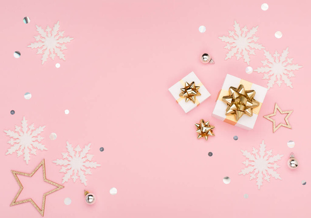 Weihnachtsgrußkarte Vorlage. Goldene und silberne Dekorationen, festliche Geschenke, Schneeflocken auf rosa Hintergrund. Weihnachten, Winter, Neujahrskonzept. Flache Lage, Draufsicht, Kopierraum. - Foto, Bild