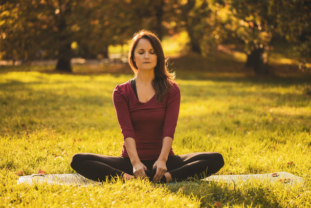 Beautiful woman sitting in lotus position and meditating in the nature,Padmasana/Lotus position. - Fotó, kép