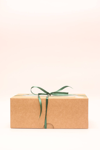 Vertical photo of a box of kraft paper tied with a green ribbon on a white background - Photo, Image