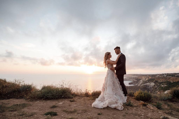 portrait of a happy bride in luxury dress and groom, wedding at sunset - Photo, image