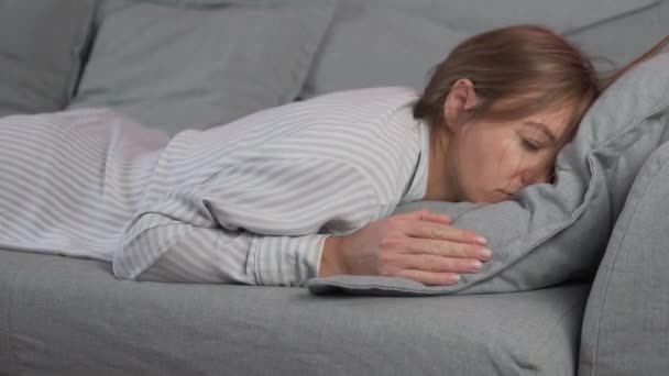 Zmęczona śpiąca kobieta upada na sofę bez siły i zasypia w ciągu dnia w domu - Materiał filmowy, wideo