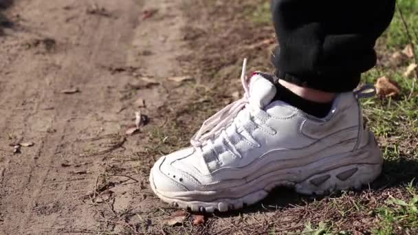 λευκά sneaker χτυπά στο έδαφος σε εξωτερικούς χώρους κατά τη διάρκεια της ημέρας στον ήλιο - Πλάνα, βίντεο