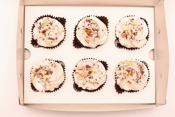 Six brownies au chocolat à la crème blanche dans une boîte artisanale ouverte par le haut sur une assiette blanche. Image de vue supérieure - Photo, image