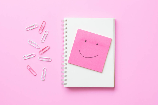 Poste-o papel nota desenho rosto sorriso emotion.Pink papel nota pegajosa com notebook no fundo rosada.Pensamento positivo no espaço de trabalho - Foto, Imagem