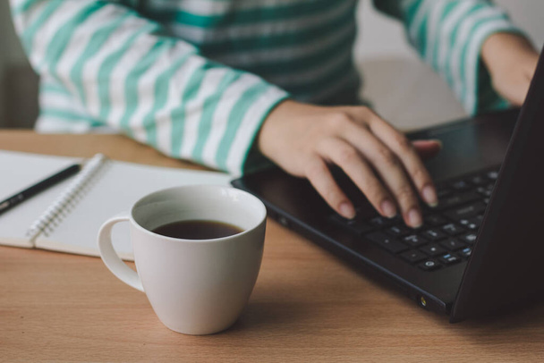 Tasse Kaffee mit Geschäftsfrau, die mit Laptop am Schreibtisch arbeitet. - Foto, Bild