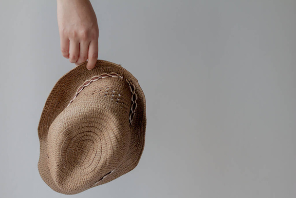 Women carrying straw hat on gray background. - Photo, Image