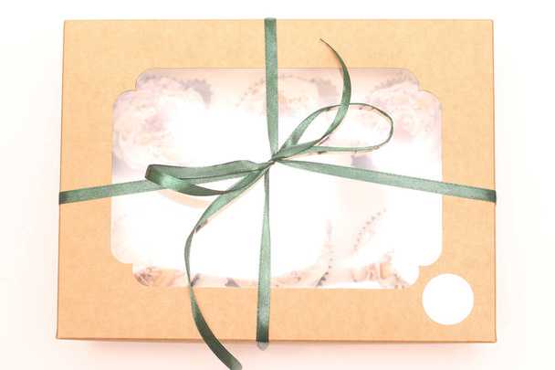 Caja de regalo artesanal con una parte superior transparente y dulces en el interior atados con una cinta verde sobre un fondo blanco. Estudio de regalo foto vista superior - Foto, imagen